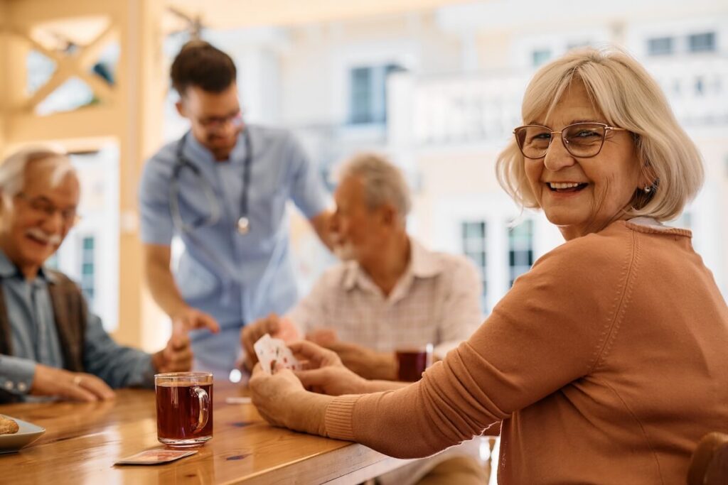 Older woman playing cards and smiling over her shoulder