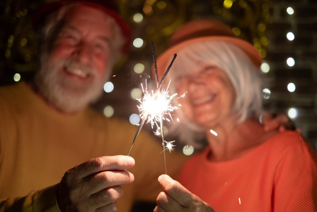 Couple of older adults holding sparklers.