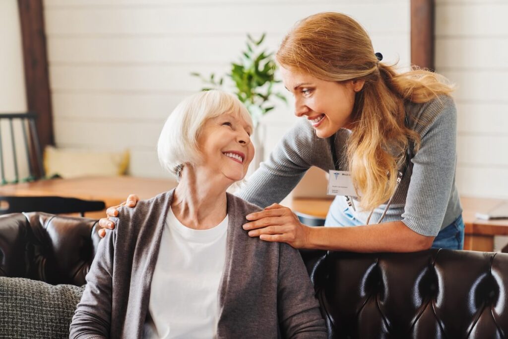 Middle aged nurse taking care of old woman indoors.